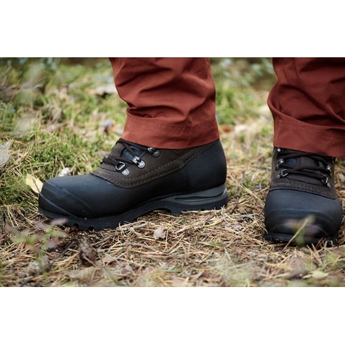 En persons f&#248;tter i svarte sko p&#229; gress.
