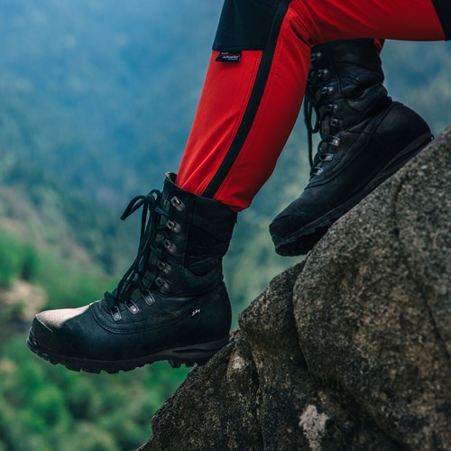 Een persoon met zwarte laarzen en zwarte laarzen op een rots.