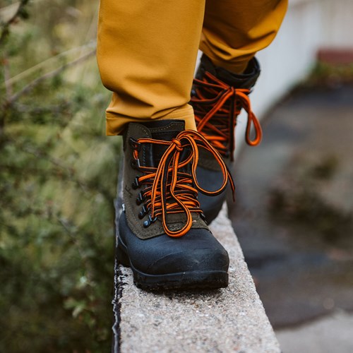 A person wearing a black and orange shoe.