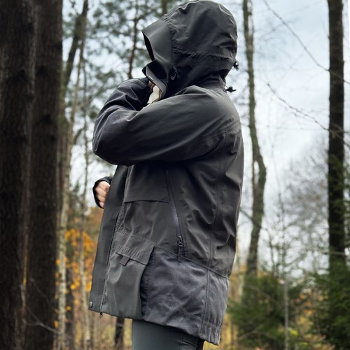 A person wearing a hoodie and standing in the woods.