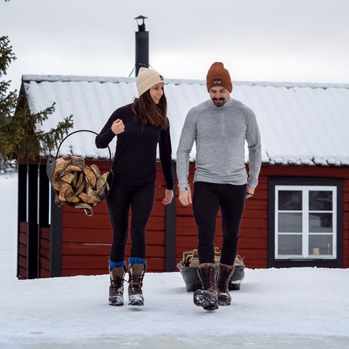 A man and woman standing in the snow with a basket on their backs.