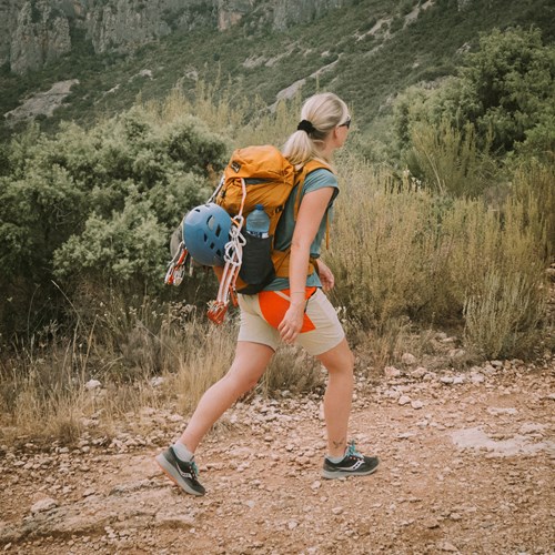 A person carrying a backpack walking on a dirt path.
