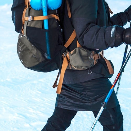 A person with a backpack walking on a snowy mountain.