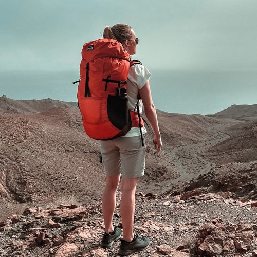 A man with a backpack on a rocky hill.